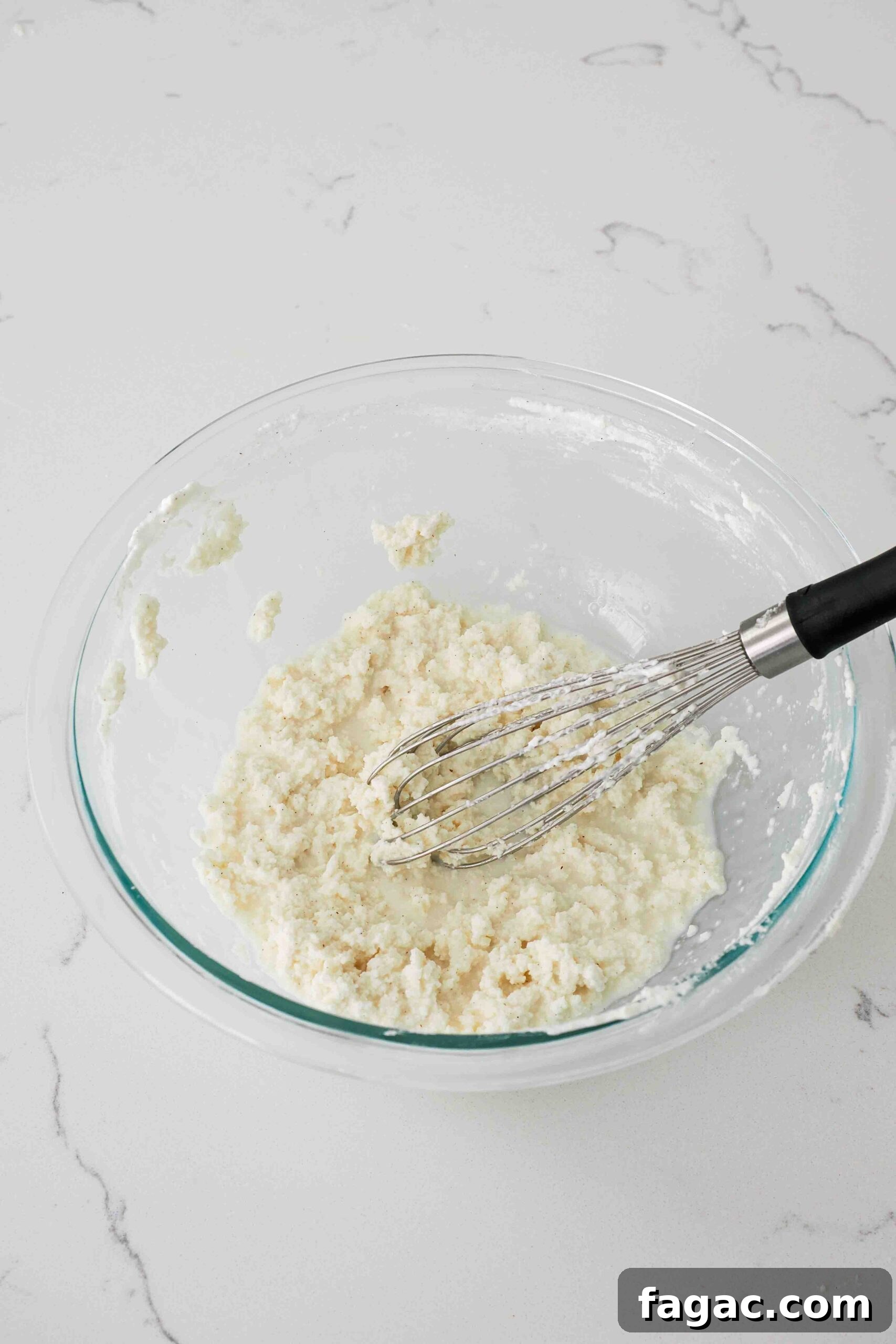 Silky Vanilla Whipped Cream Recipe for Desserts and Toppings 7 Overwhipped heavy cream is clumpy in a glass bowl.
