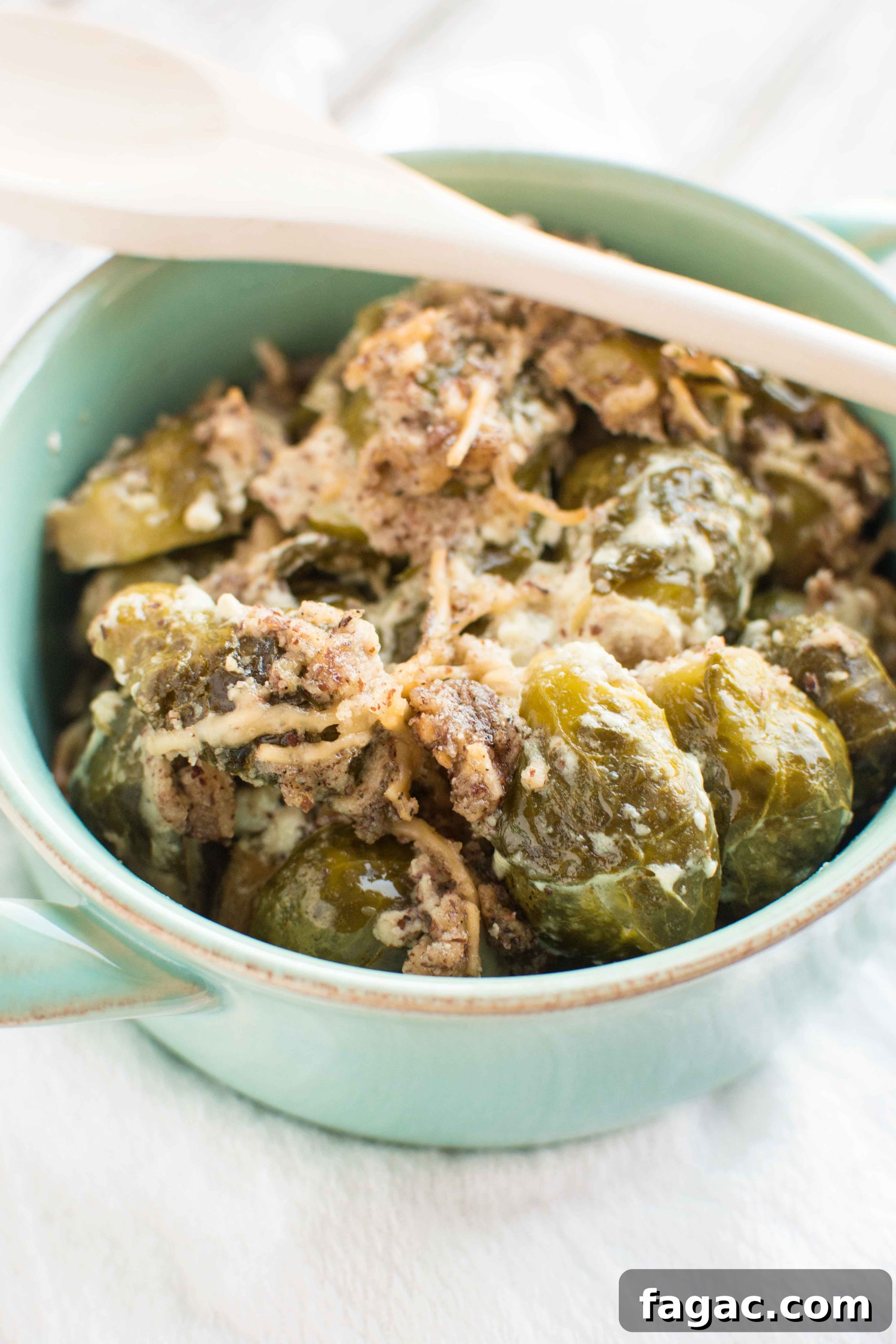 brussels sprouts in green bowl with white wooden spoon across bowl