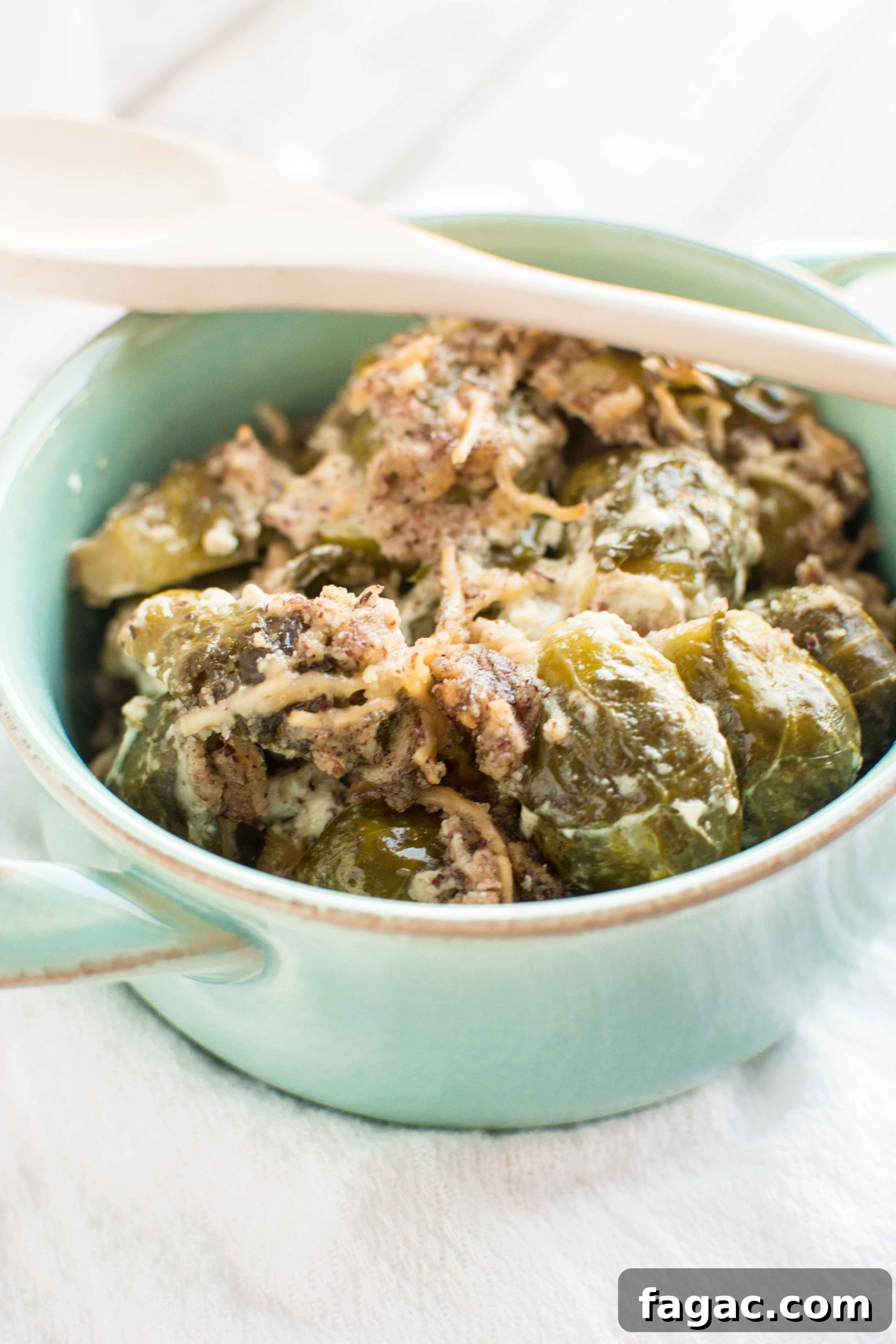 brussels sprouts in green bowl with wooden spoon across bowl