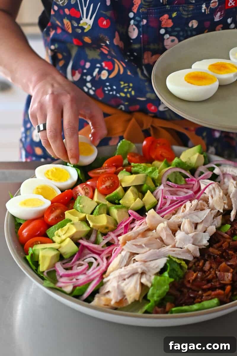 Placing halved hard boiled eggs on a Cobb salad.