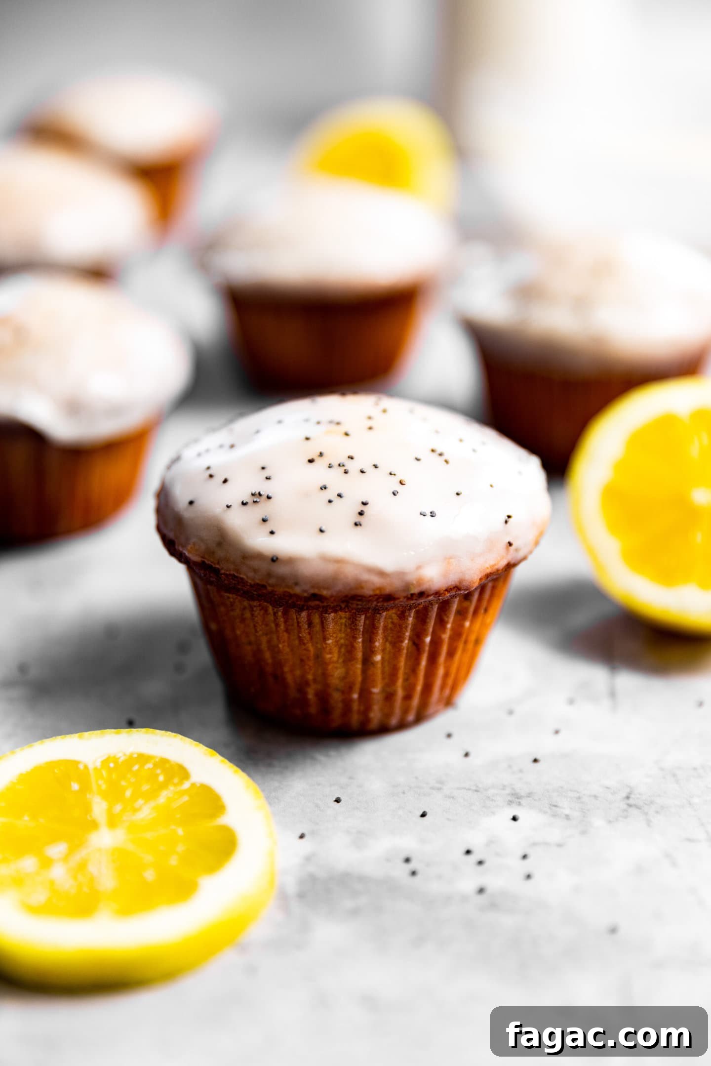 Close up of glazed lemon poppy seed muffins next to lemon slices