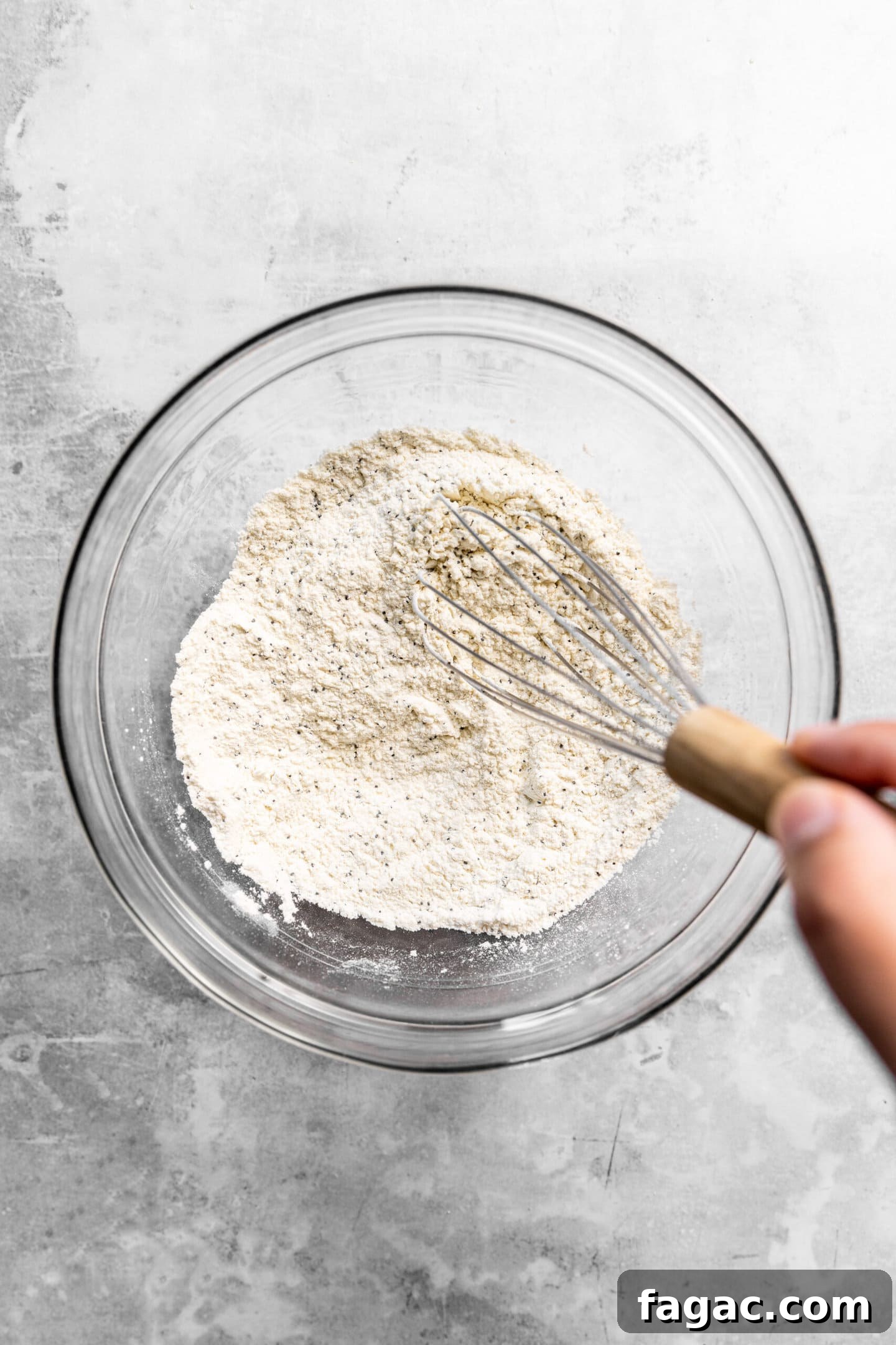 Flour, baking powder, baking soda, salt, and poppy seeds being whisked together.