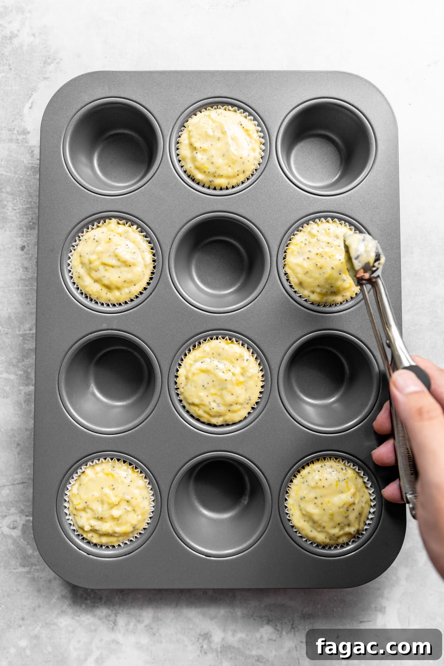 Muffin batter being scooped into muffin pan.