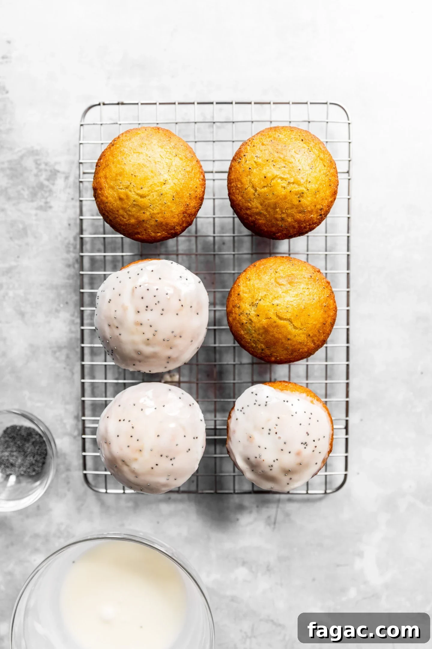 Muffins being dipped into lemon glaze and sprinkled with poppy seeds.
