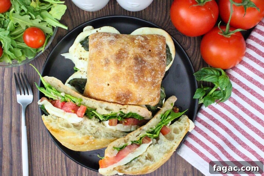 overhead view of two air fryer caprese sandwiches on a black plate showing off the fresh ingredients and melty cheese