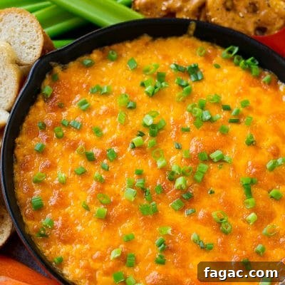 Creamy Buffalo Ranch Chicken Dip Recipe for Game Day 7 Buffalo ranch chicken dip topped with melted cheese and green onions, surrounded by vegetables, pretzels and baguette slices.
