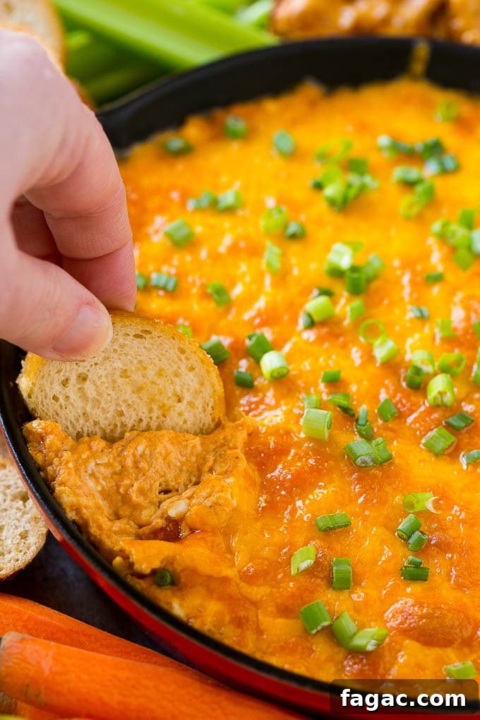 Buffalo Ranch Chicken Dip Baked buffalo chicken dip with a baguette slice scooping some out.