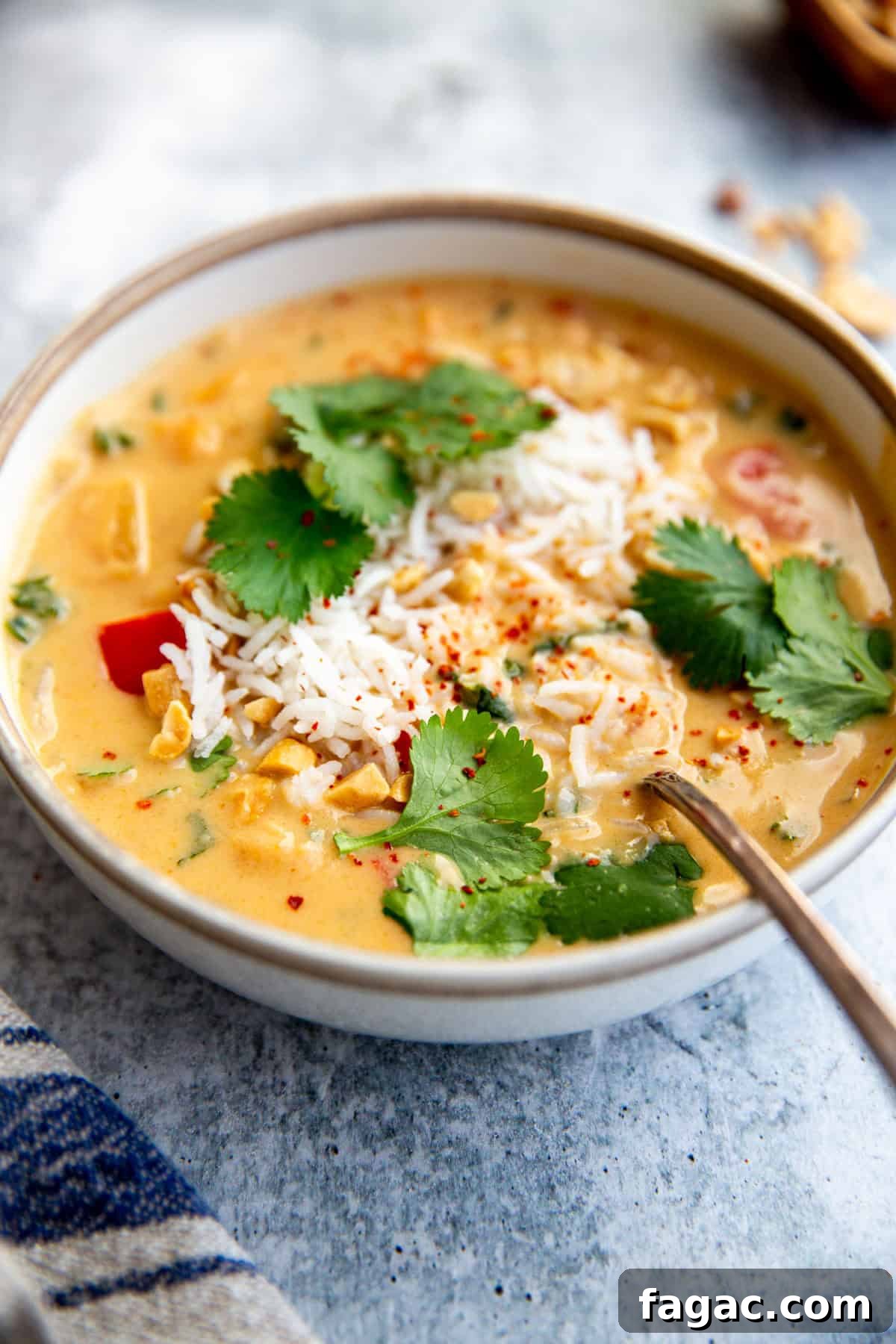 a creamy, hot bowl of west african inspired sweet potato and peanut stew in a bowl topped with fresh herbs and chopped peanuts
