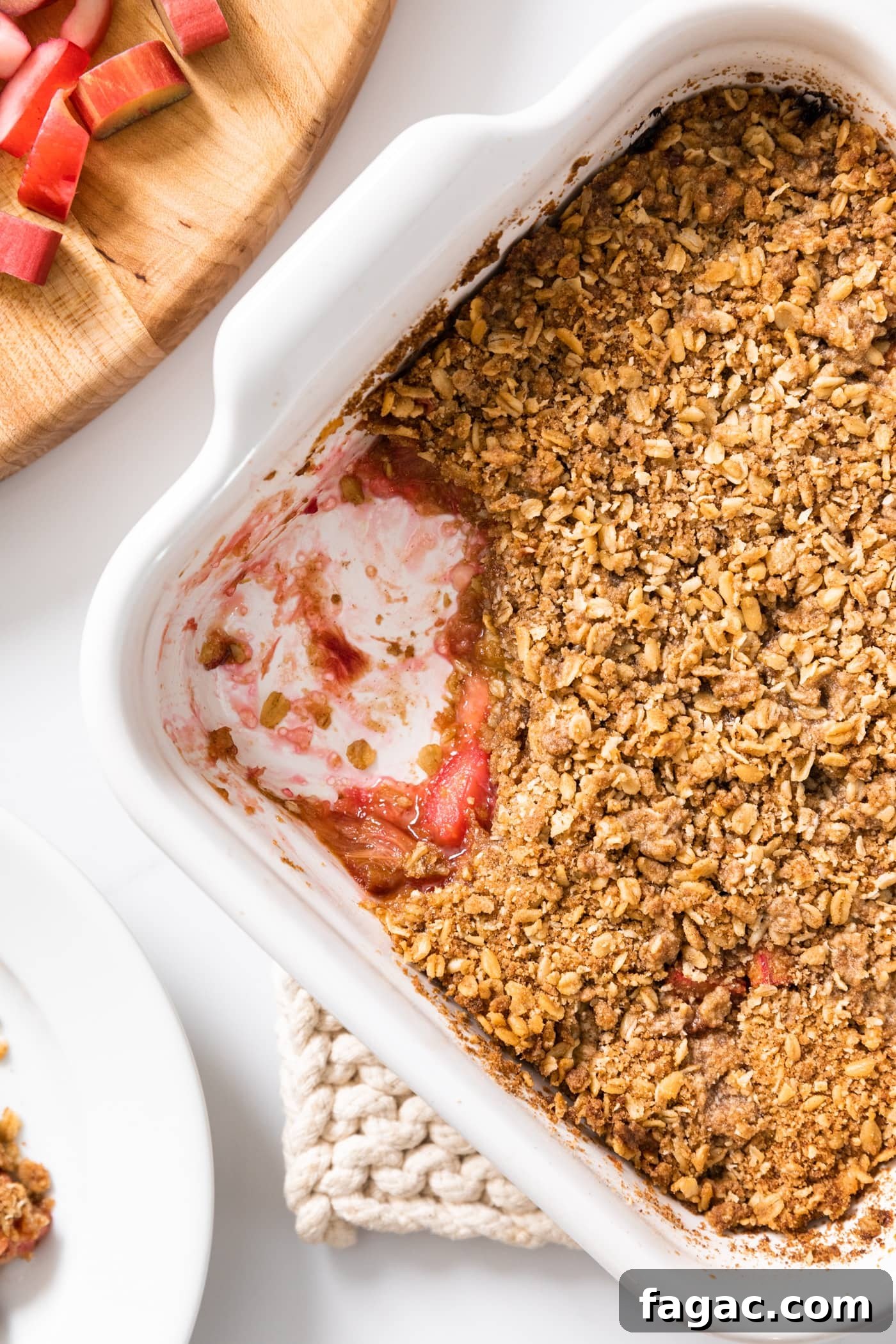 Classic Rhubarb Crisp Recipe with Buttery Oat Topping 3 Top down view of white baking dish filled with rhubarb crisp with light brown topping with a scoop taken out