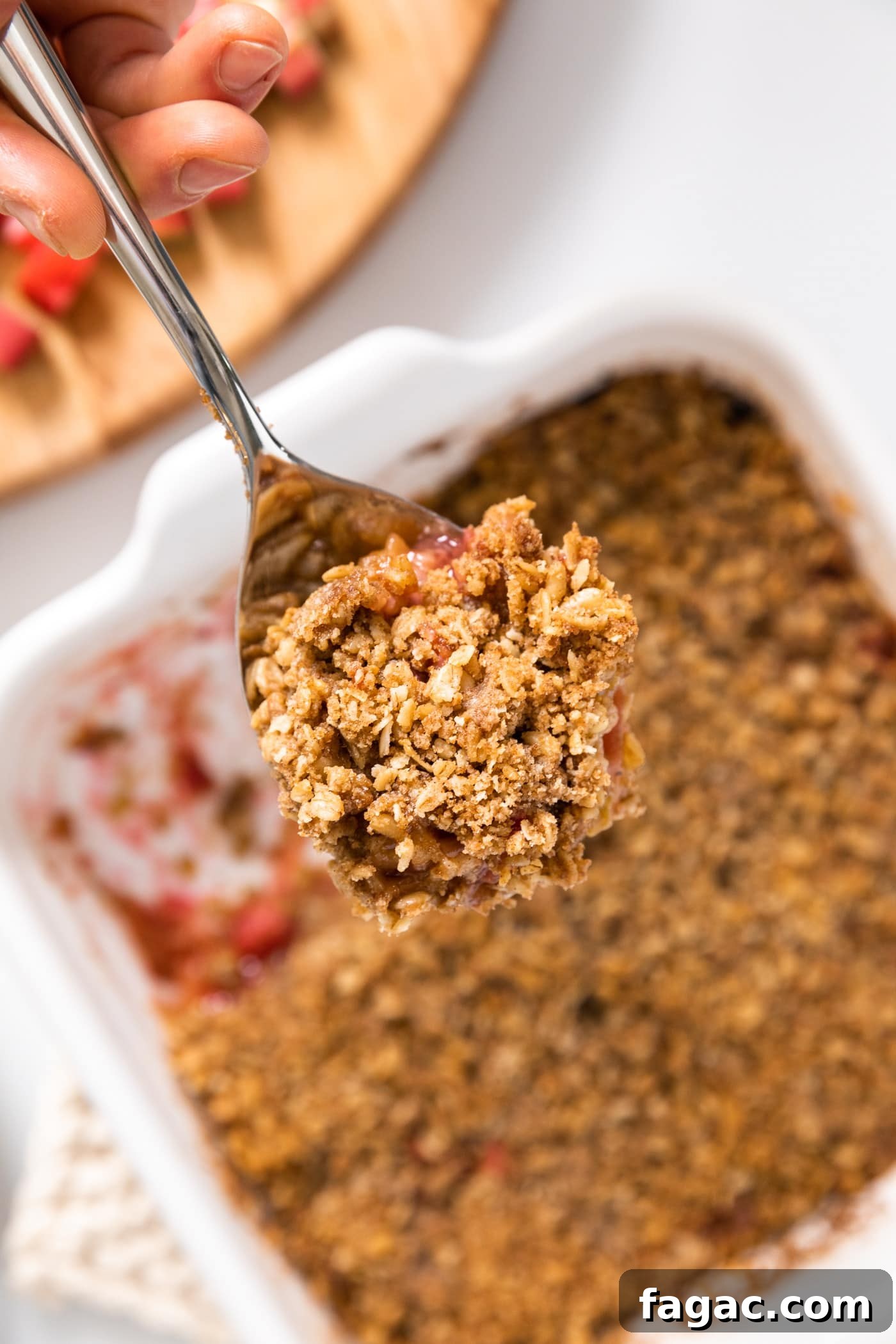 Classic Rhubarb Crisp Recipe with Buttery Oat Topping 4 Large spoon holding scoop of rhubarb crisp from pan below