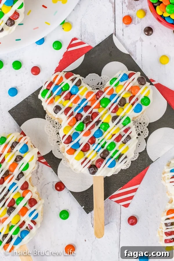 M&M's Mickey Mouse Rice Krispie Treats - chocolate and M&M's makes these rice krispie treats look and taste just like the Mickey treats in the Disney parks. A close up overhead picture of a M&M's Mickey Mouse Rice Krispie Treat on a stick