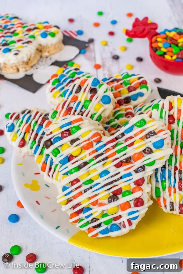 M&M's Mickey Mouse Rice Krispie Treats - a Mickey Mouse cookie cutter makes these rice krispie treats look just like the Mickey treats in the Disney parks. A close up picture of a plate of M&M's Mickey Mouse Rice Krispie Treats on a Disney plate with M&M's scattered around it
