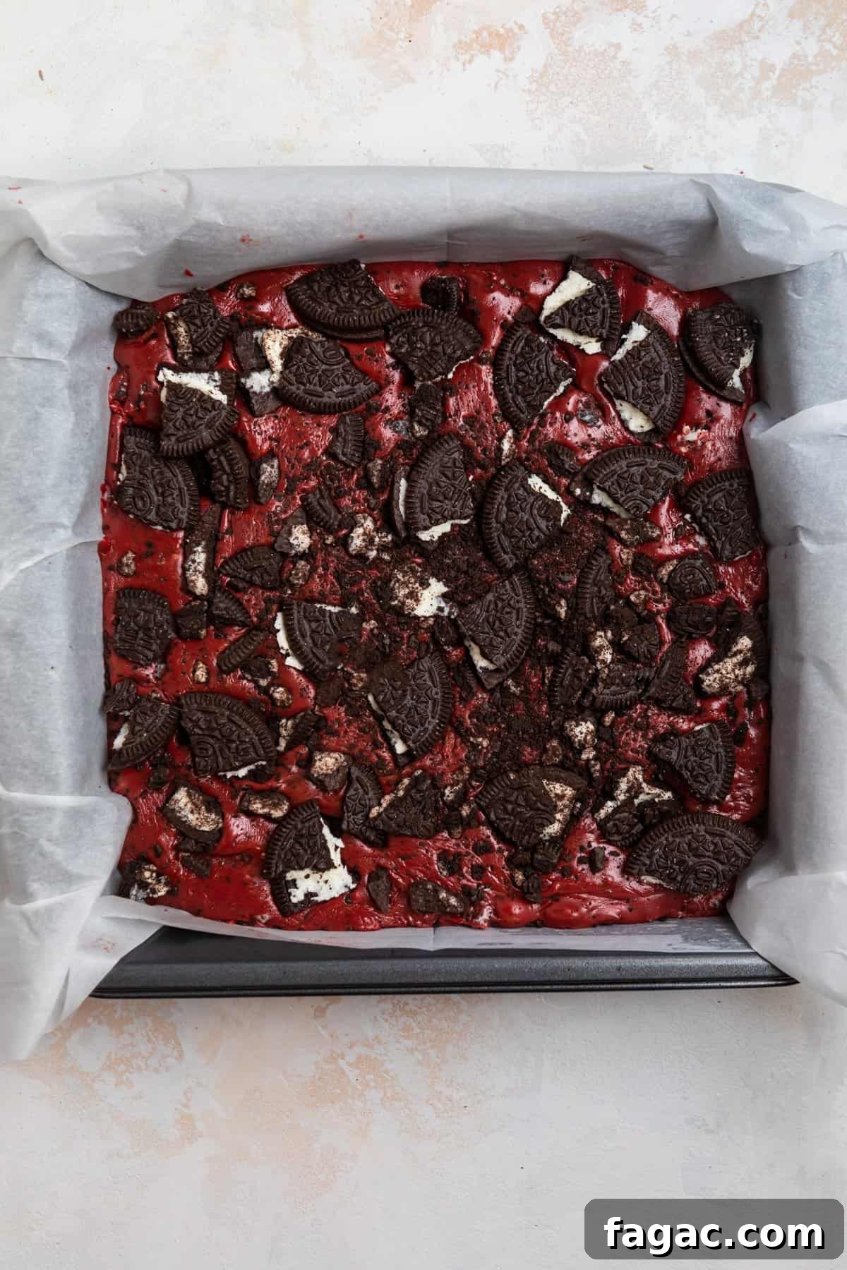 Decadent Red Velvet Oreo Fudge Recipe for Dessert Lovers 7 Prepared fudge in parchment lined baking pan and topped with crushed up Oreos.