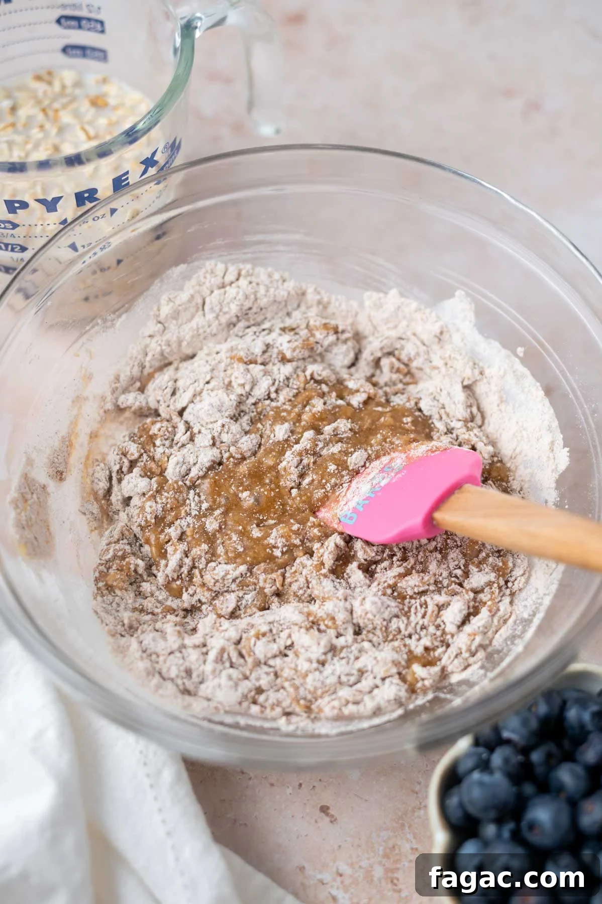 dry ingredients being mixed into wet ingredients in a bowl with a spatula