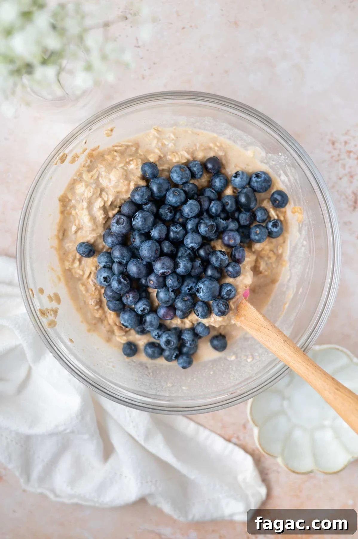 fresh blueberries on top of batter in a bowl with a spatula