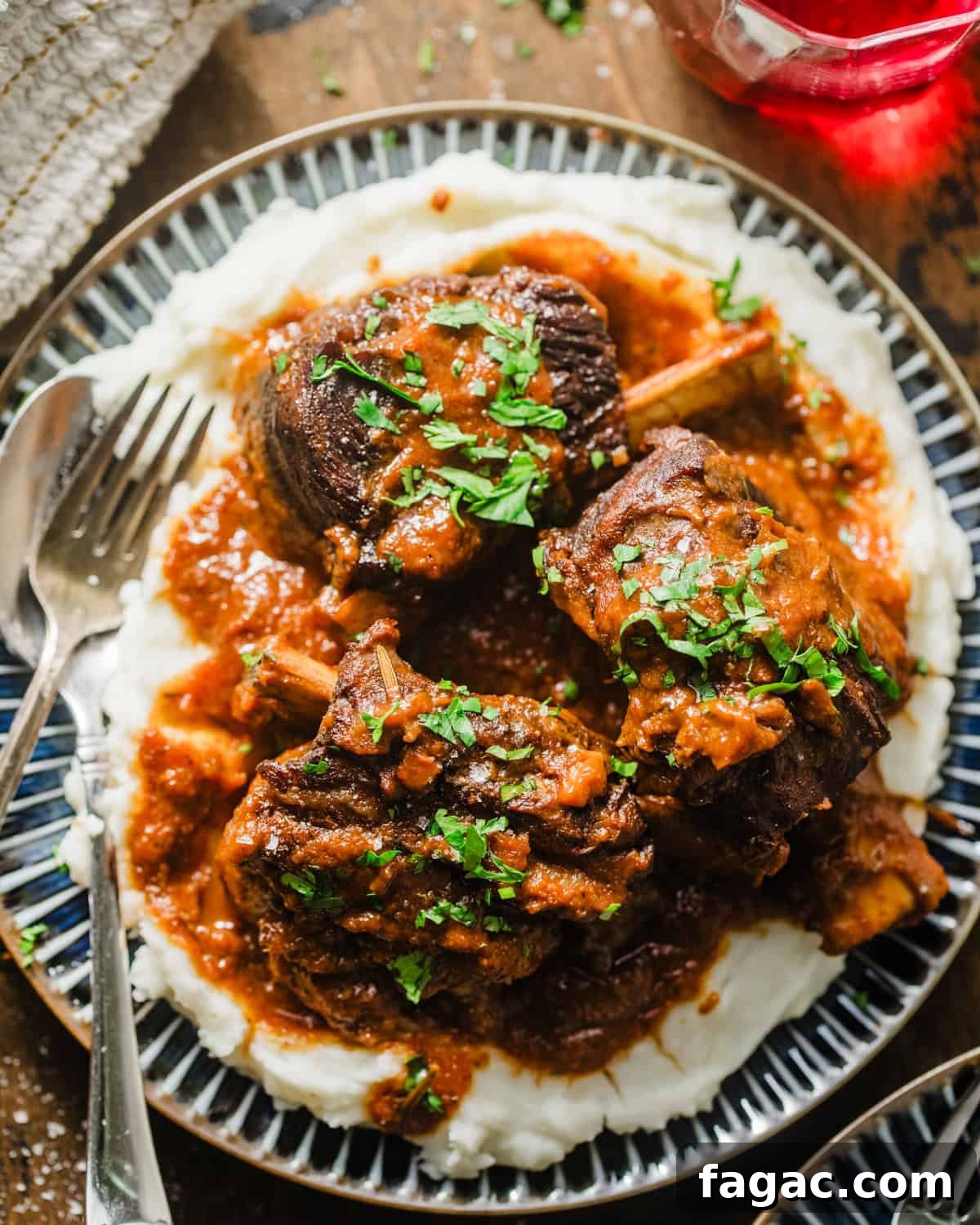 red wine braised short ribs on a plate with mashed potatoes and garnished with parsley.