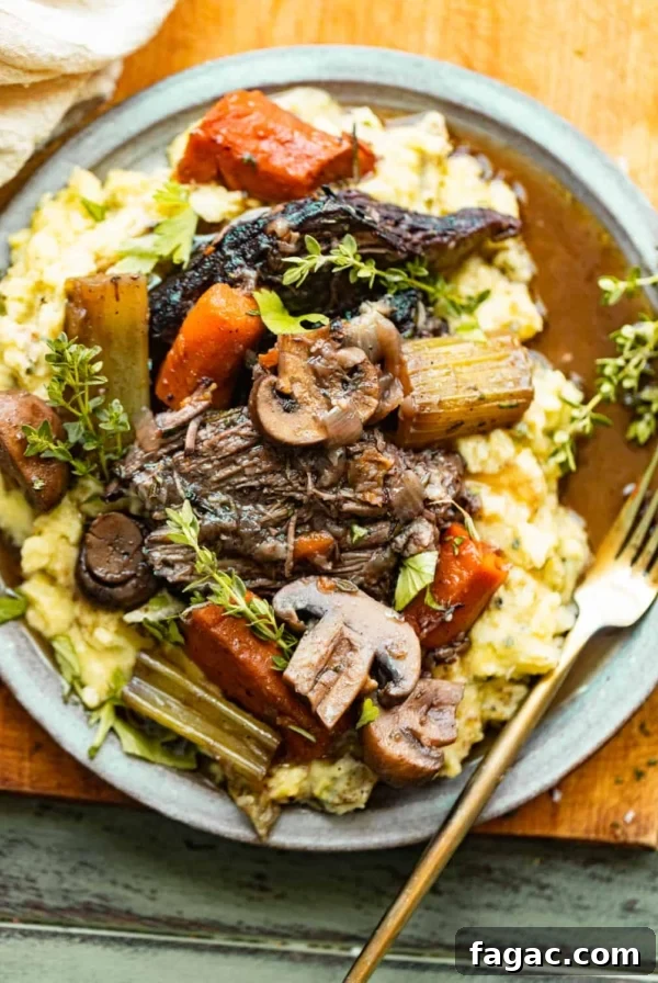 oven baked chuck roast on a plate with mashed potatoes and veggies.