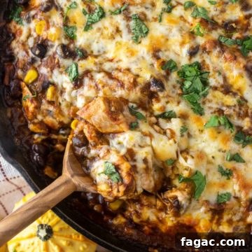 Spoon dipped in turkey tamale pie in cast iron skillet.