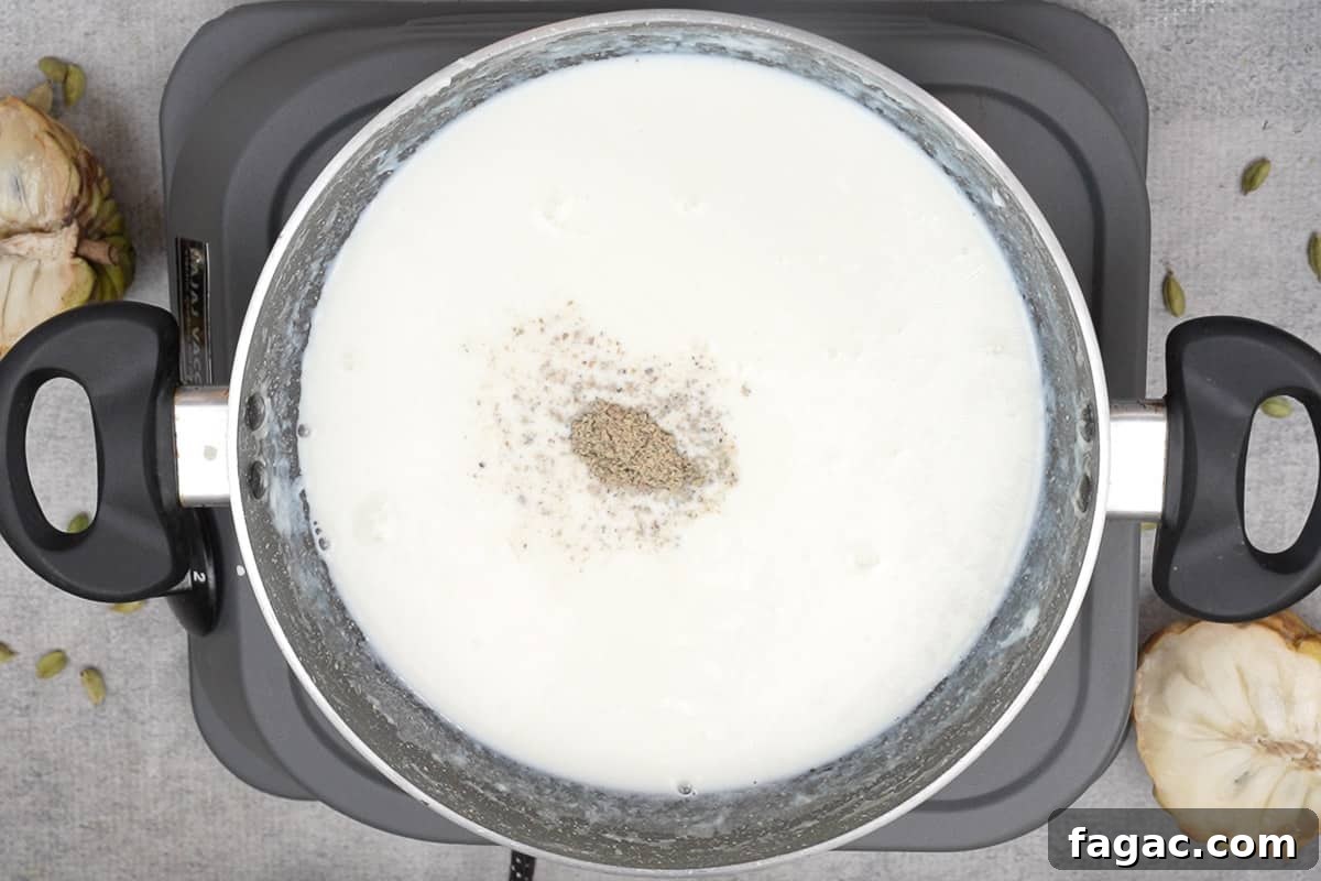 Sugar and cardamom powder added to reduced milk.
