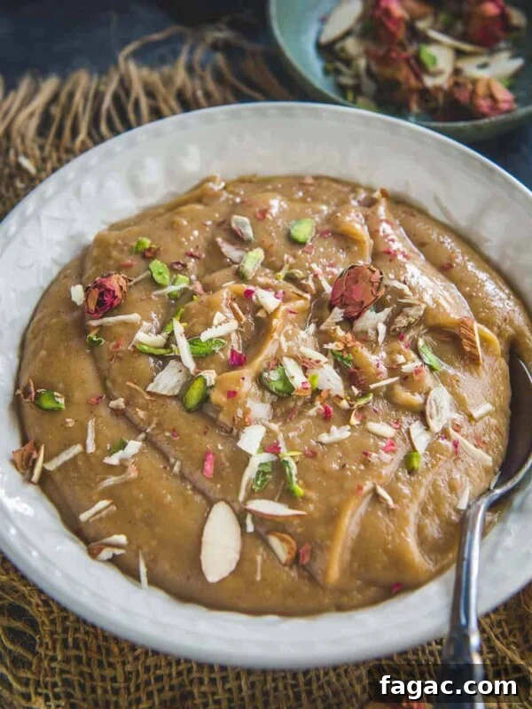 A white bowl filled with creamy Besan Halwa, garnished with sliced almonds, pistachios, and dried rose petals.