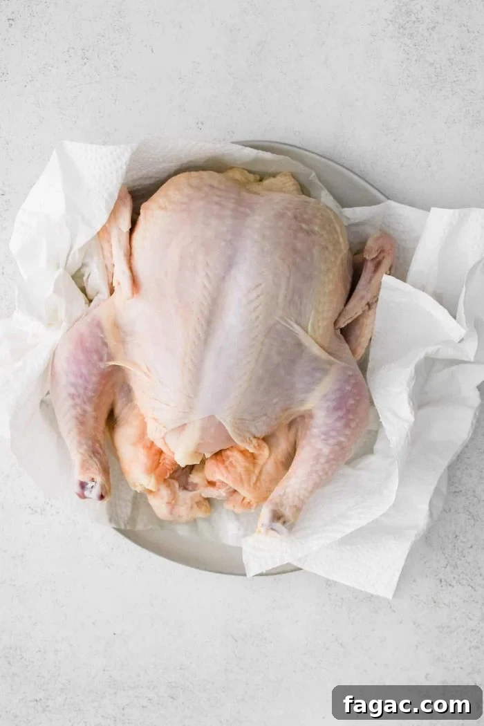 Crispy Roast Chicken with Herb Butter and Lemon 3 Raw, uncooked whole chicken on a plate lined with paper towels.