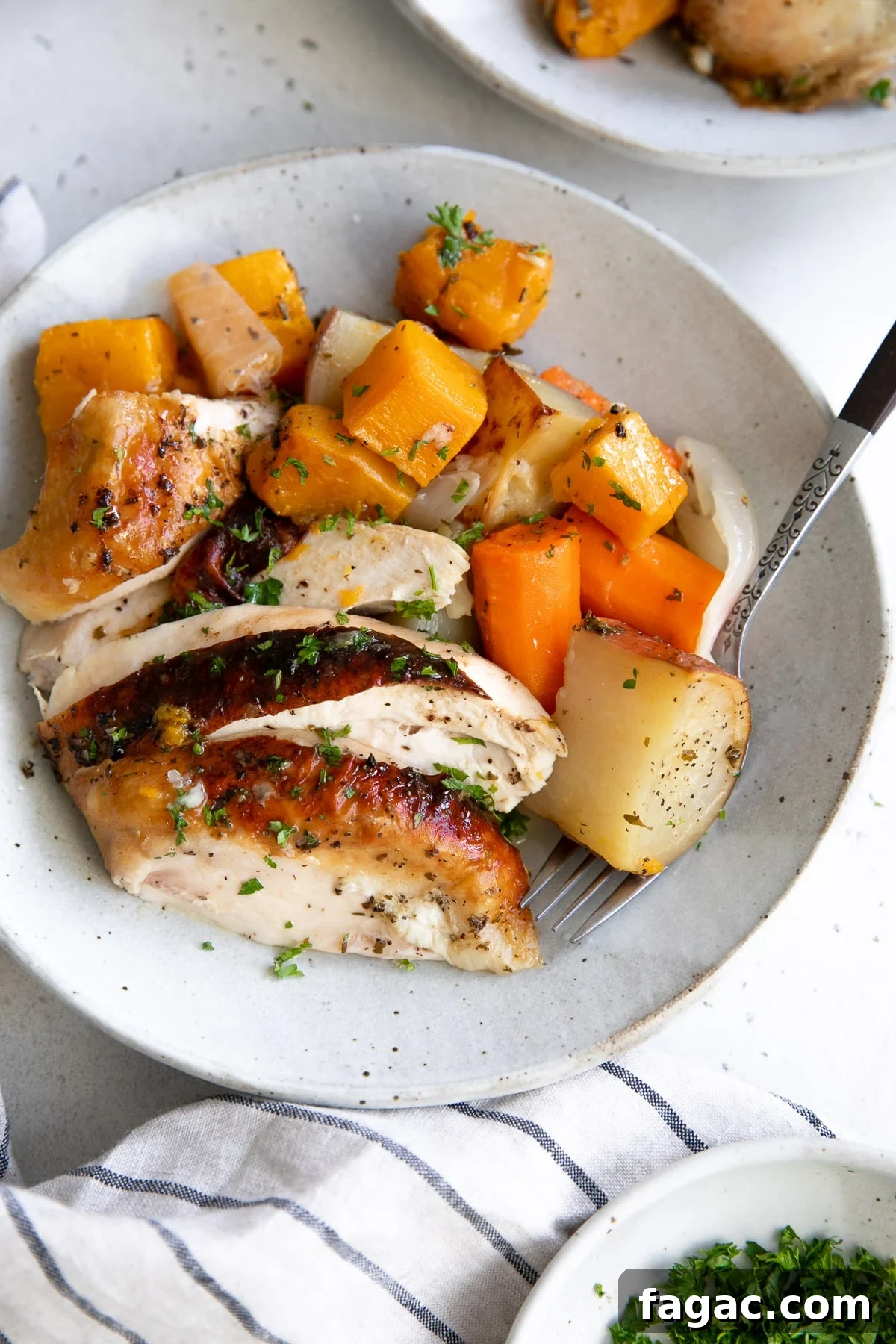 Crispy Roast Chicken with Herb Butter and Lemon 9 Plate filled with sliced roast chicken breast served with tender roasted vegetables.