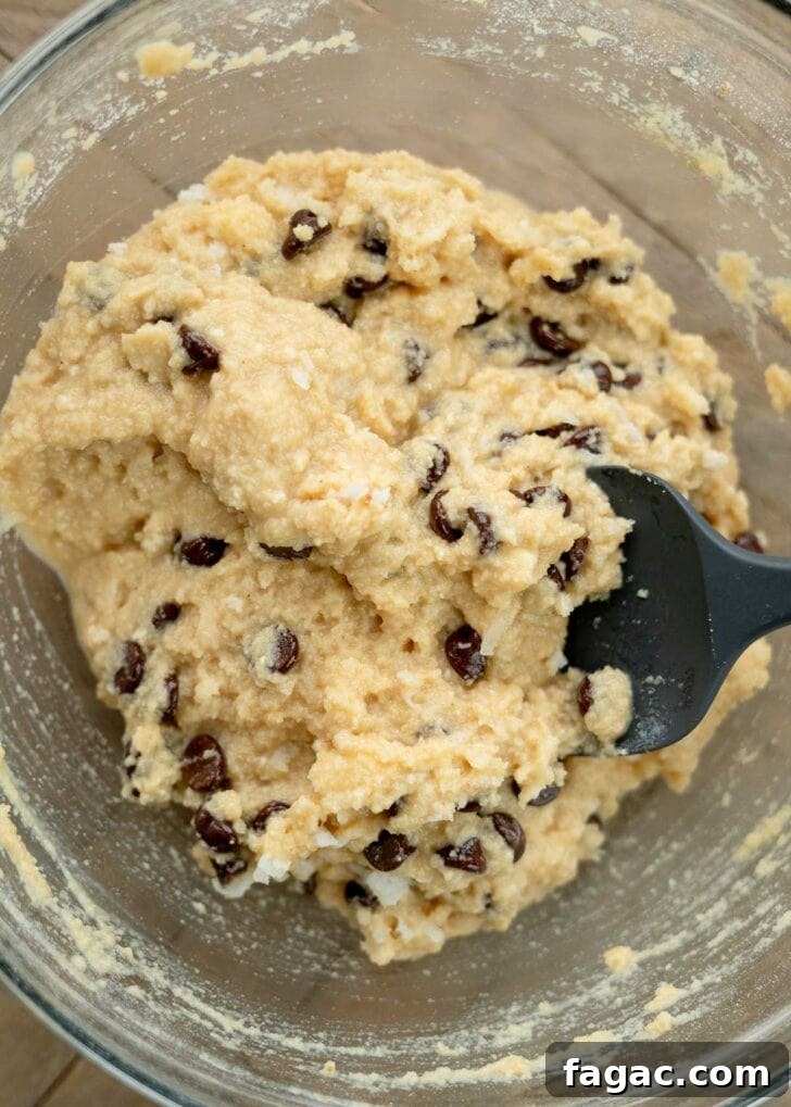 Coconut Flour Muffins: Moist, Low-Carb Recipe for Beginners 10 silicone spatula folding in chocolate chips and coconut flakes for low-carb muffins