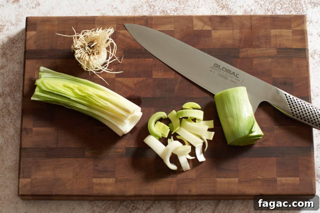 Braised Pork with White Beans, Wine & Fresh Sage 6 Sliced leeks on a cutting board with a knife.