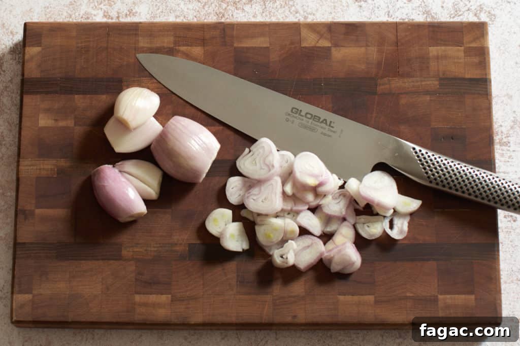 Braised Pork with White Beans, Wine & Fresh Sage 7 Sliced shallots on a cutting board with a knife.