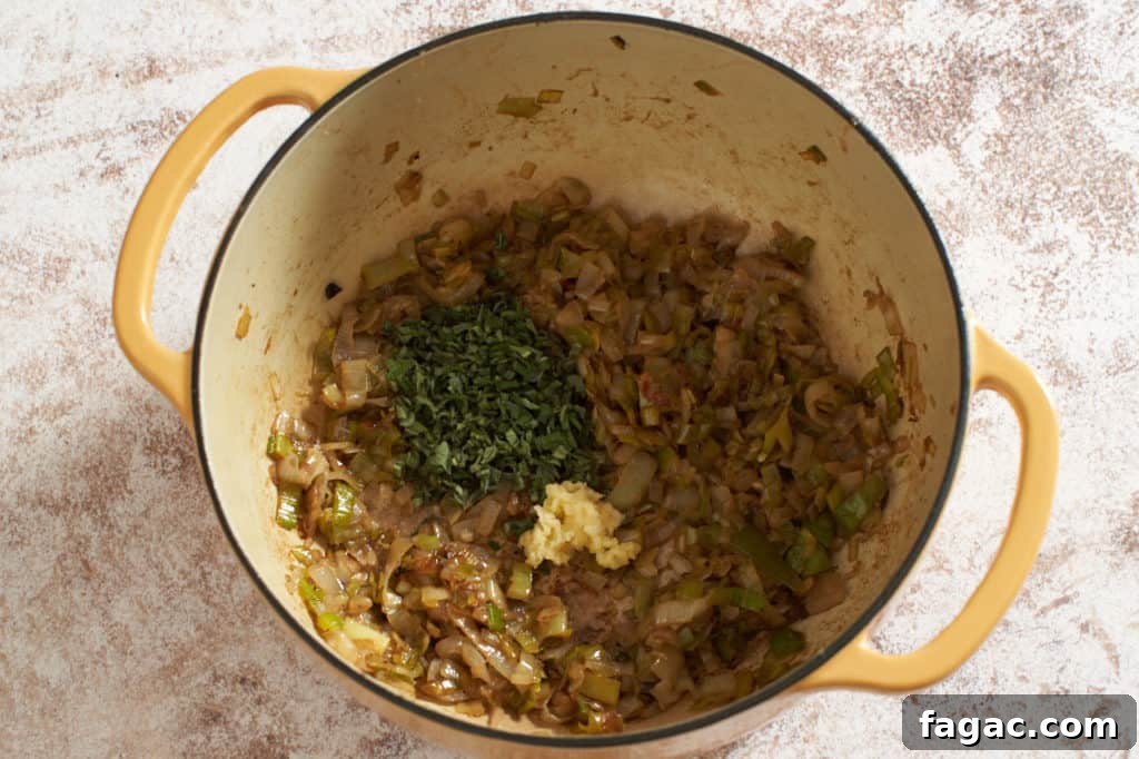 Braised Pork with White Beans, Wine & Fresh Sage 9 A yellow Dutch oven with cooked leeks and shallots topped with chopped sage and garlic.