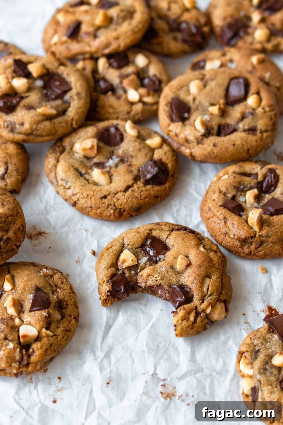 Brown butter chocolate chip cookies scattered on a white surface.