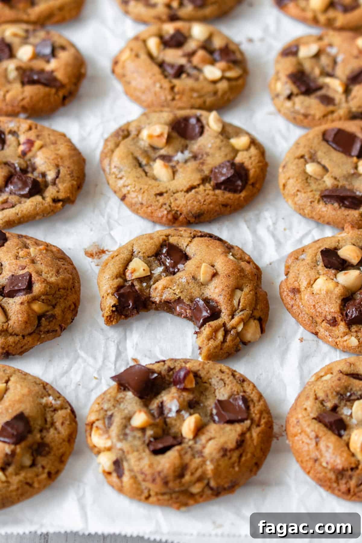 Brown butter chocolate chip cookies laid out in rows, with one having been bitten.