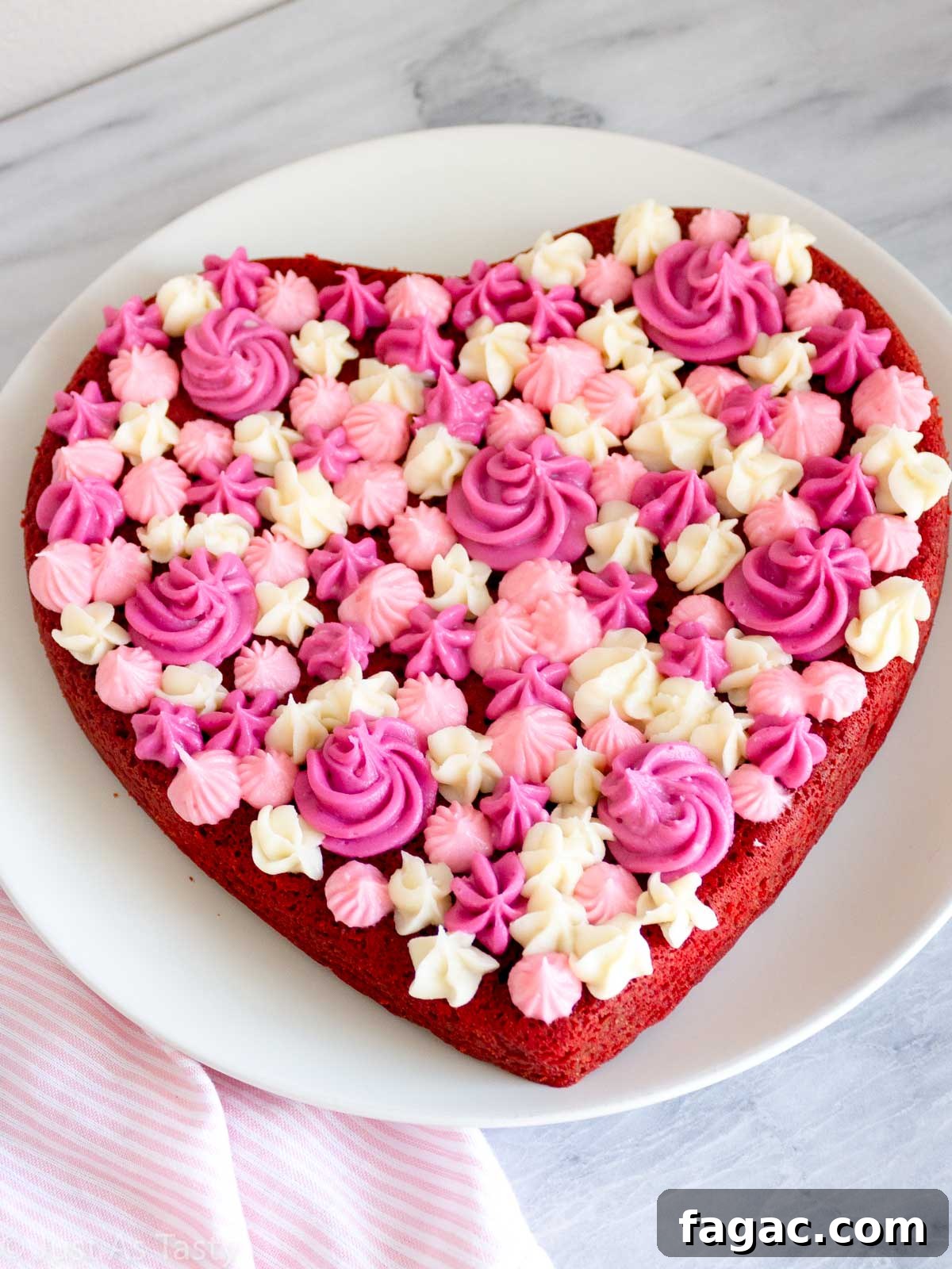 Gluten-Free Red Velvet Cake Recipe — Moist, Classic Flavor 2 Heart shaped gluten free red velvet cake with pink and white piped cream cheese frosting on top.
