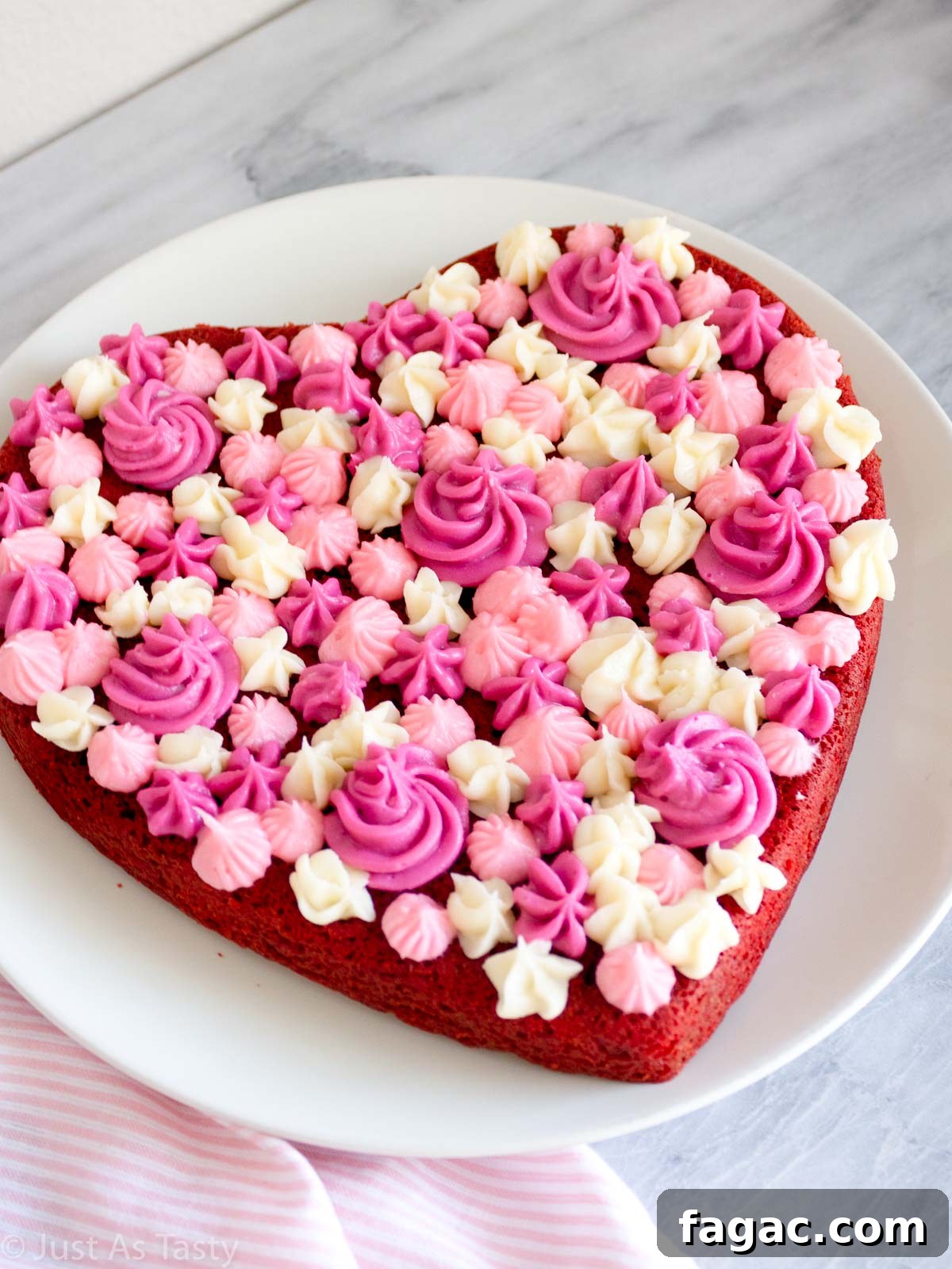 Gluten-Free Red Velvet Cake Recipe — Moist, Classic Flavor 11 Heart shaped gluten free red velvet cake with pink and white piped frosting on top.