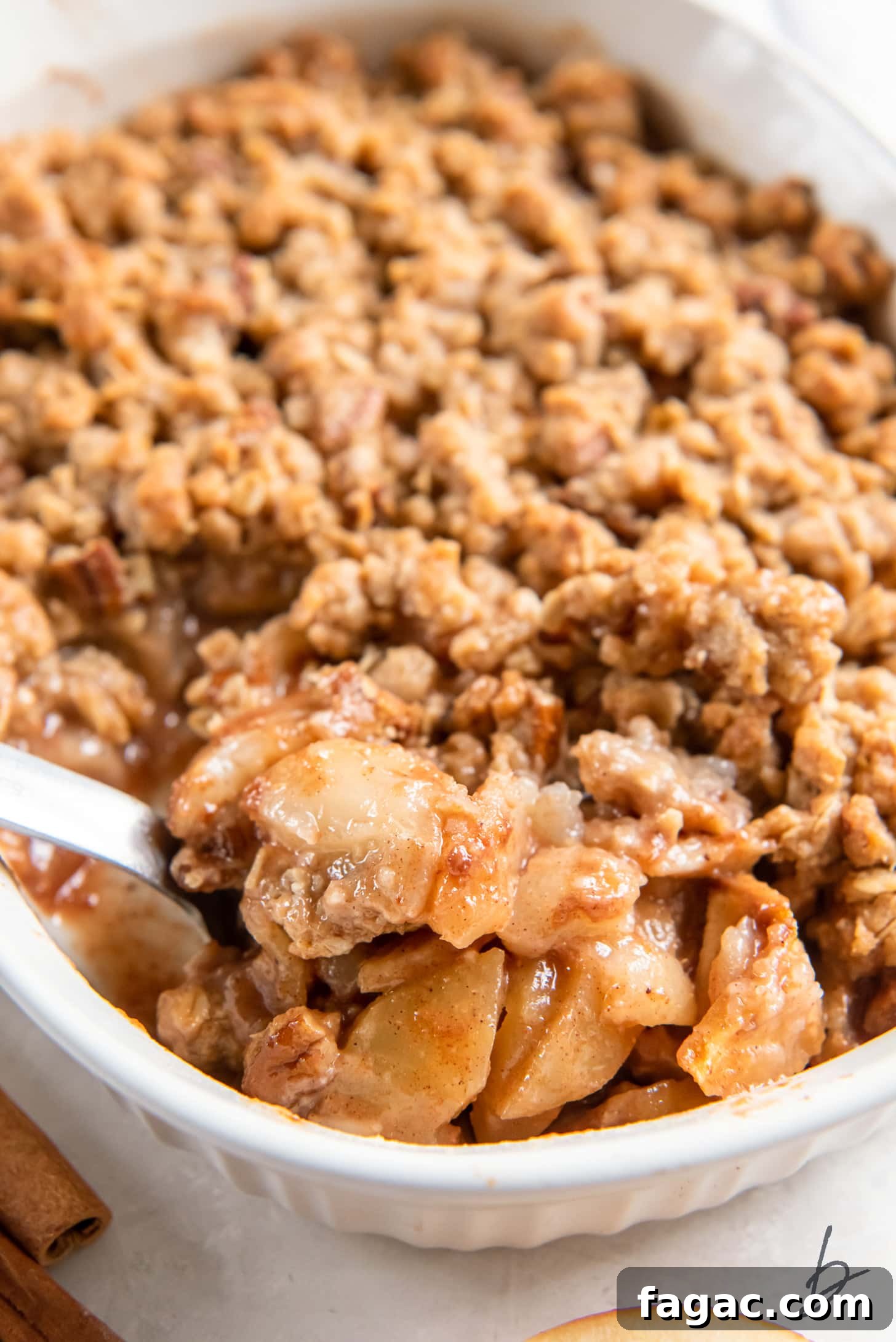 Ina Garten-Style Apple Pear Crisp Recipe 5 serving spoon lifting scoop of apple pear crisp from a baking dish.
