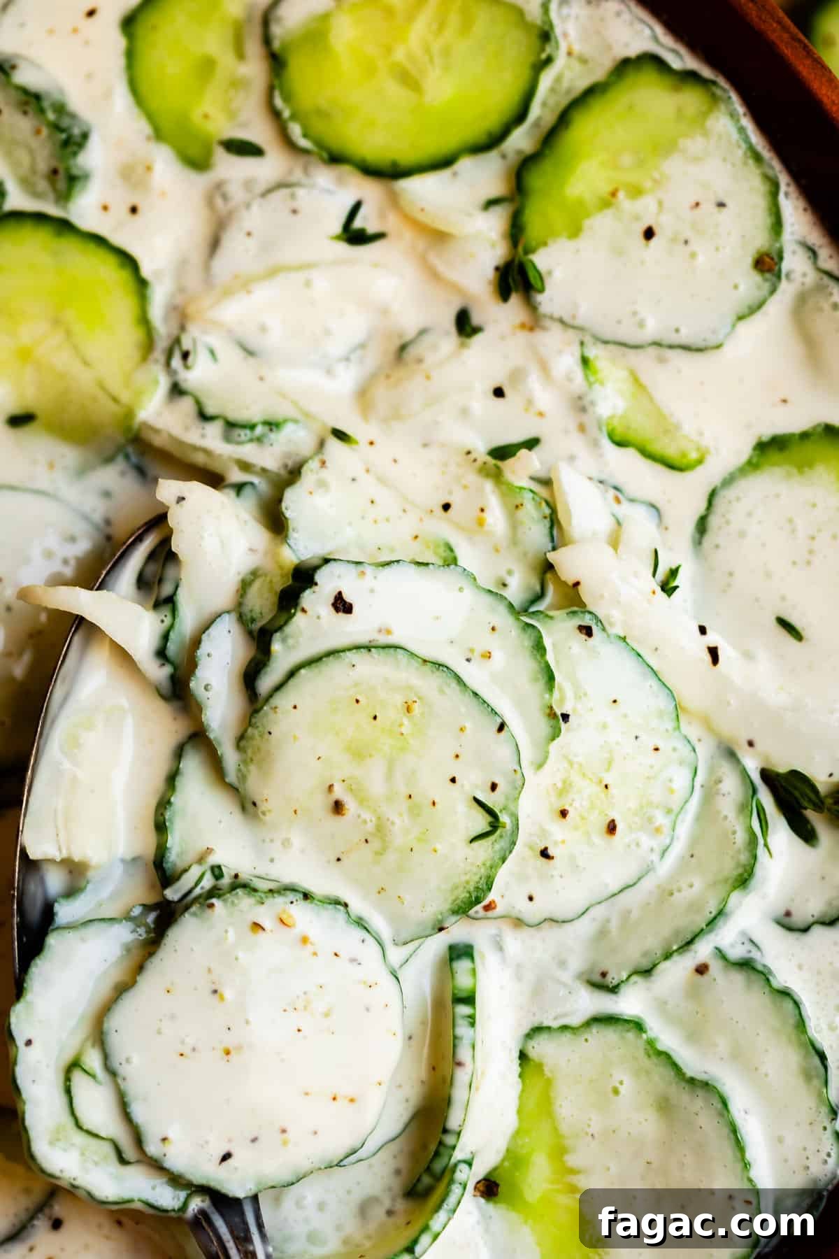 Aunt Joy’s Creamy Cucumber Salad Recipe for Summer Sides 12 cucumber salad recipe shot from overhead with a creamy sauce and spoon in the corner.