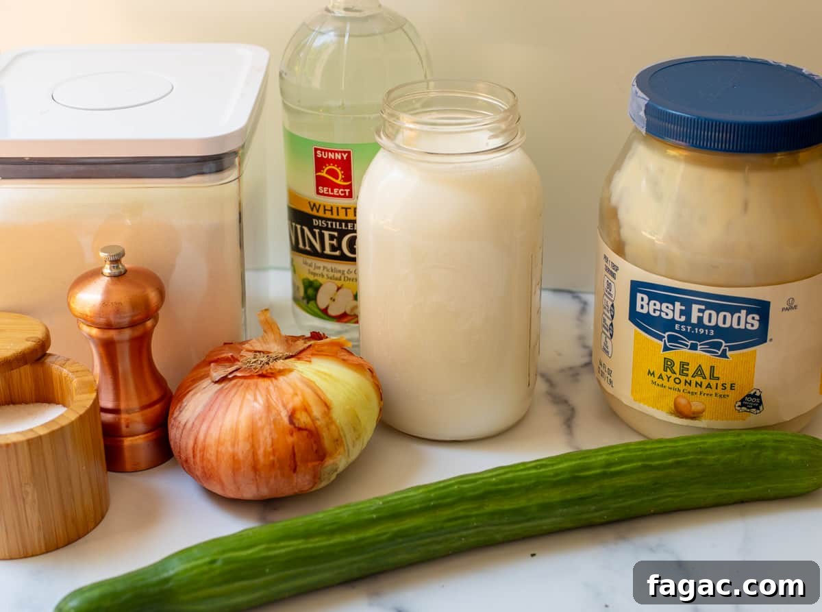 Aunt Joy’s Creamy Cucumber Salad Recipe for Summer Sides 7 Picture of ingredients laid out for cucumber salad including mayonnaise, cream, onion, English cucumber, vinegar, salt and pepper, and sugar.