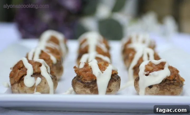 Creamy Cheese-Stuffed Mushrooms with Garlic and Herbs 2 image of stuffed mushrooms with drizzled cheese sauce over the tops