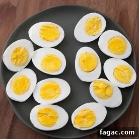 Boiled Eggs cut in half on black plate on wood board