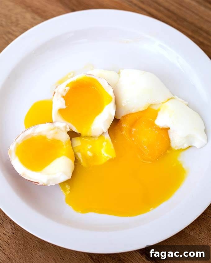 Two soft Boiled Eggs cut in half on white plate on wooden board
