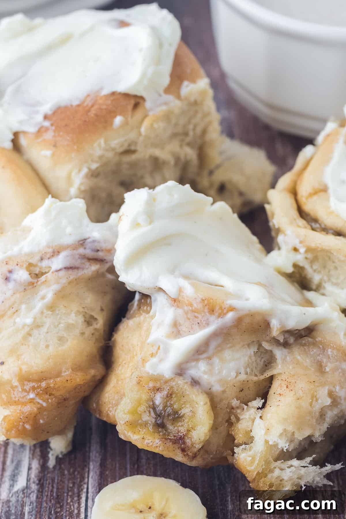 A baked cinnamon roll partially unrolled to reveal the sliced bananas inside.