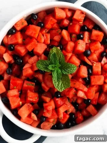 A white serving tray with cubed watermelon, blueberries and fresh mint on top.