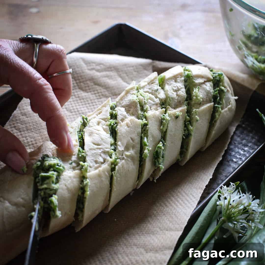 Crispy Wild Garlic Bread Recipe for Spring Gatherings 10 Womans hands spreading a small baguette with wild garlic butter