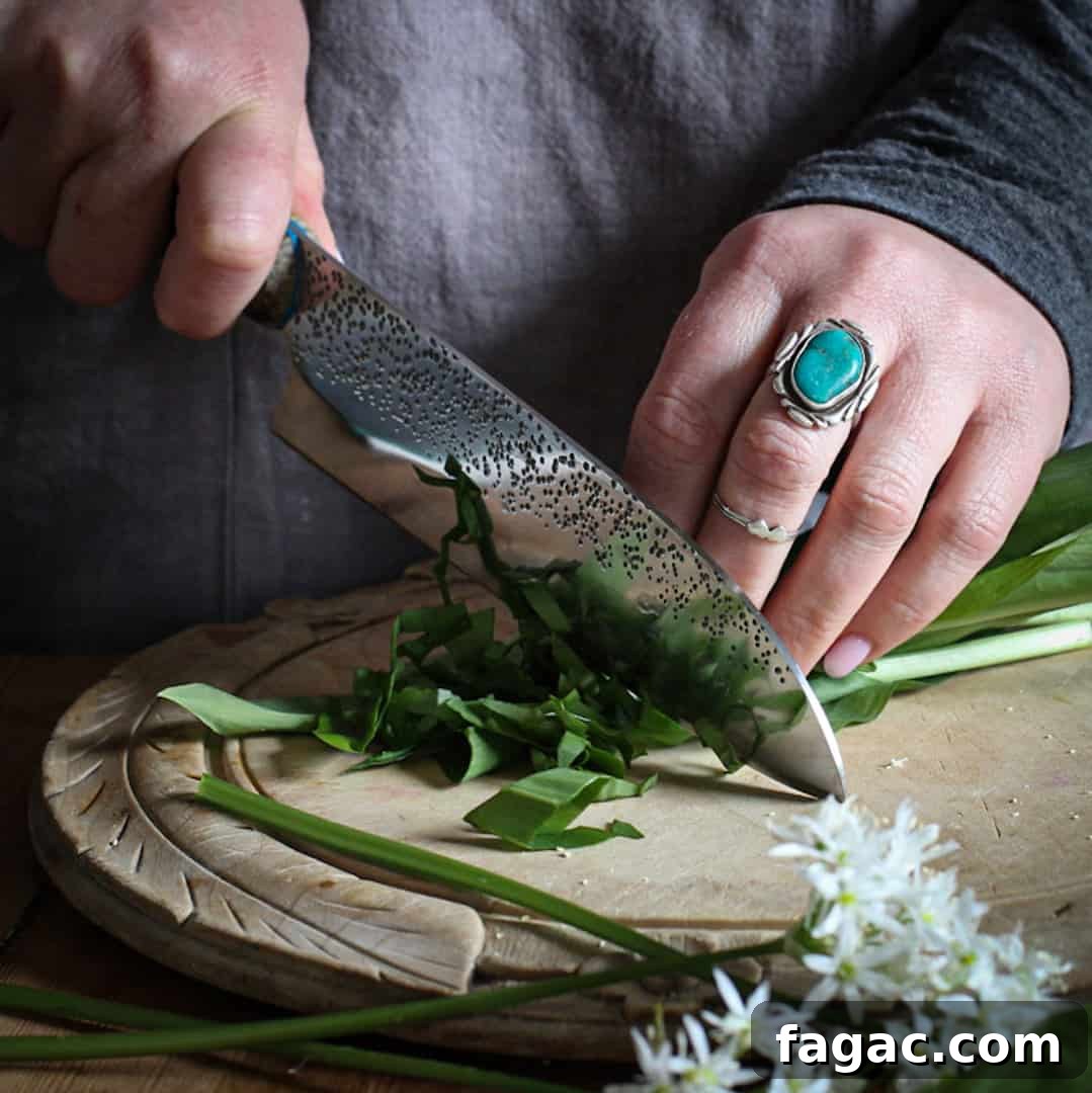 Crispy Wild Garlic Bread Recipe for Spring Gatherings 5 Womans hands chopping wild garlic leaves and flowers on a wooden chopping board