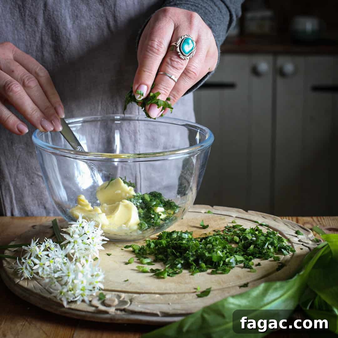 Crispy Wild Garlic Bread Recipe for Spring Gatherings 6 Womans hands adding chopped bright green wild garlic into a glass bowl of butter on a rustic wooden kitchen counter