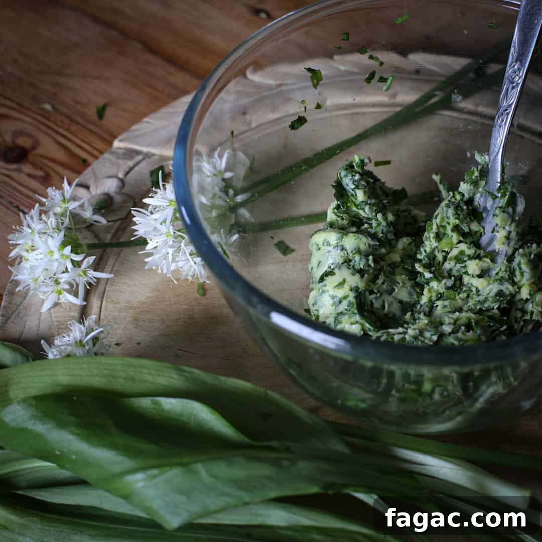 Crispy Wild Garlic Bread Recipe for Spring Gatherings 7 Glass bowl of wild garlic butter on a wooden counter with a bunch of wild ramsons