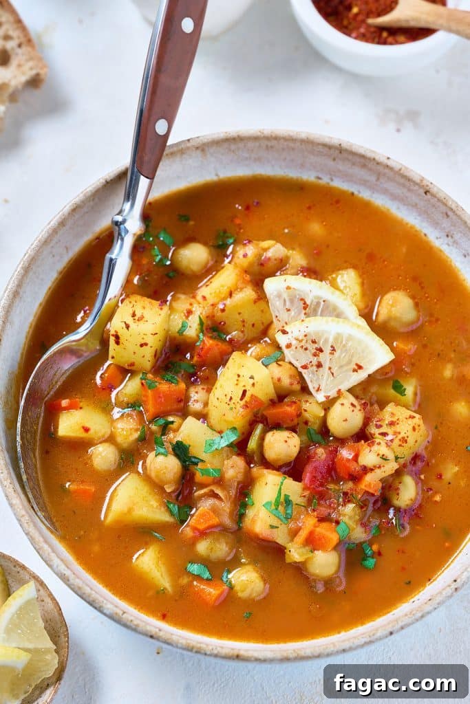 Mediterranean Chickpea Soup with Herbs and Lemon 2 A spoon scooping chickpeas and vegetable soup from a bowl.