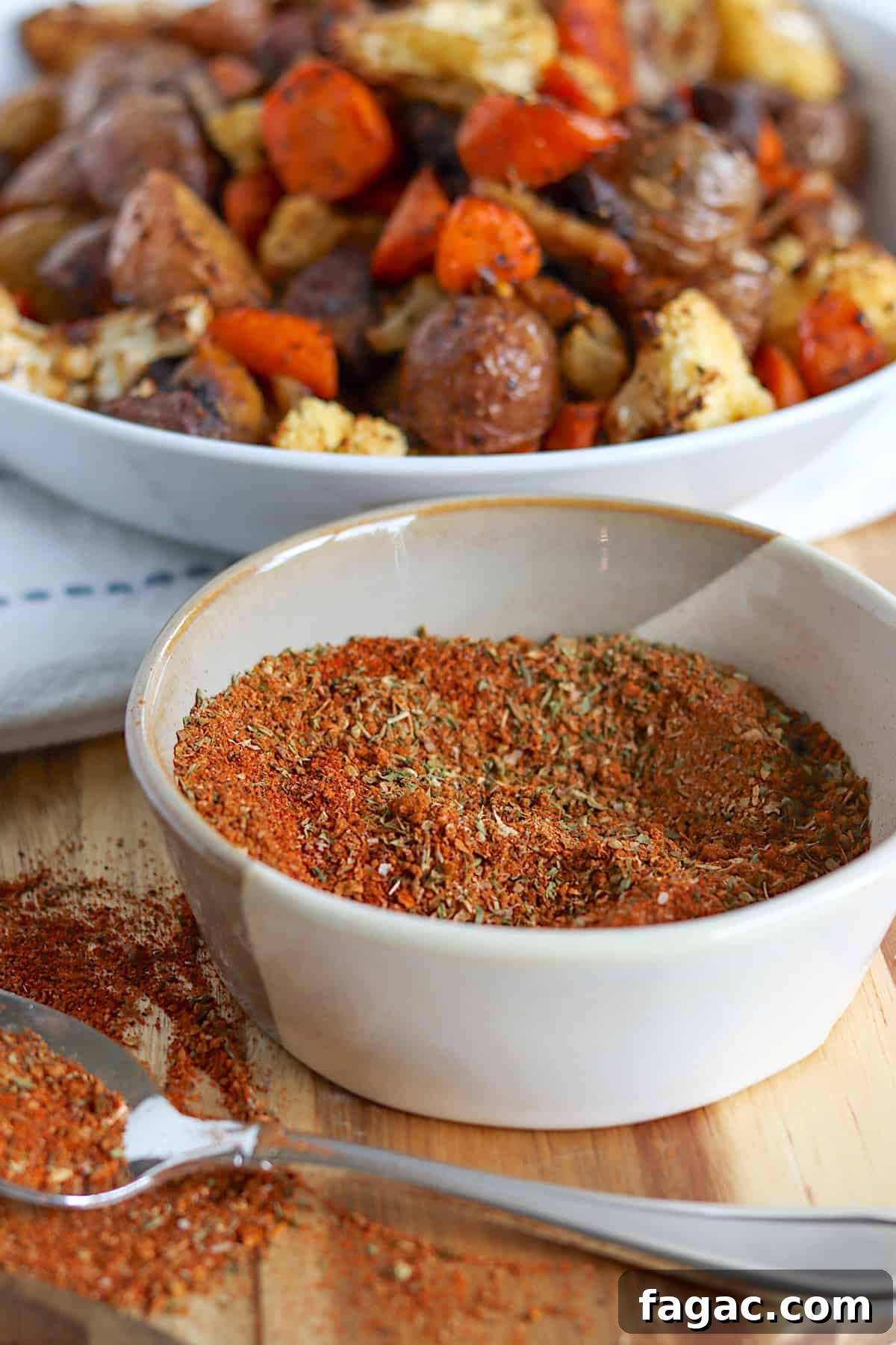 Homemade vegetable seasoning mix in a small white bowl and roasted vegetables on a platter.