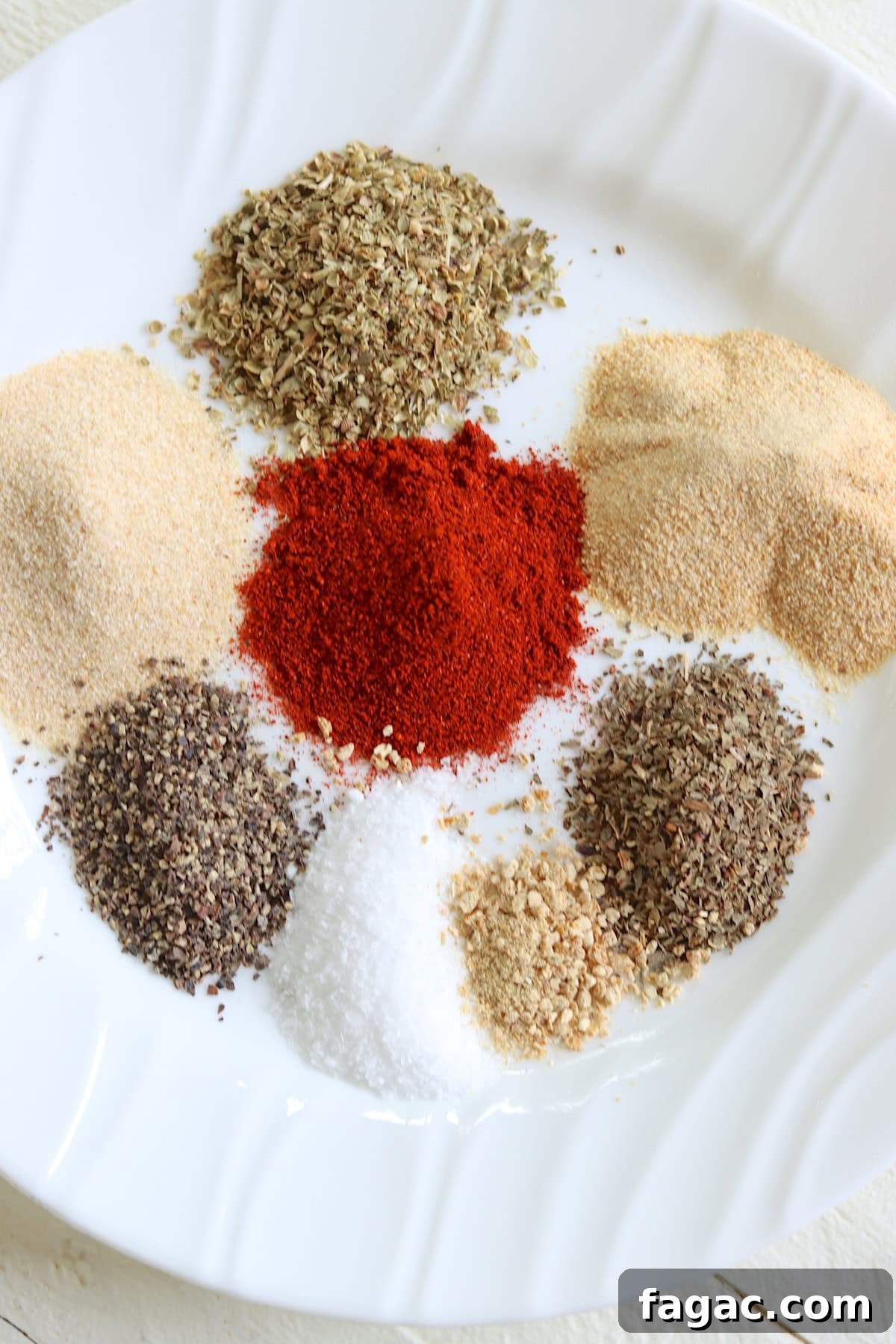 Dried herbs and seasonings on a white plate.