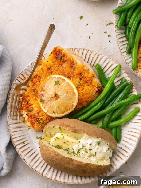 air fryer halibut on a plate with green beans and a baked potato with butter and sour cream